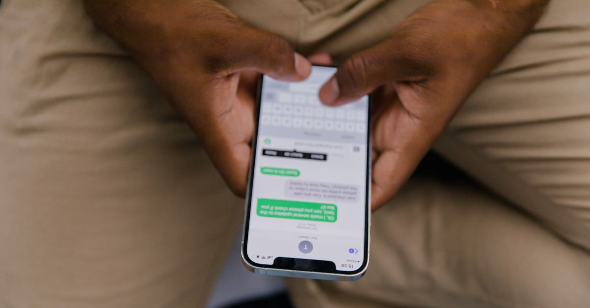 Close-up view of hands texting on a smartphone, focusing on the screen displaying messages.